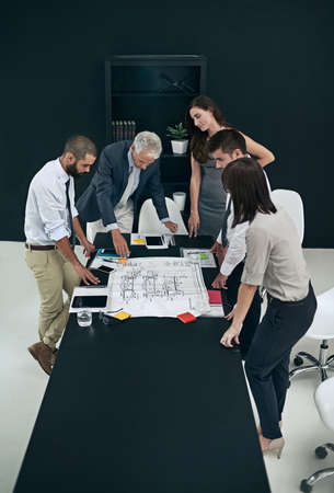 Taking a look over the plans. High angle shot of a group of businesspeople meeting in the boardroom.の写真素材