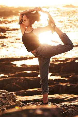 Quiet your mind and free your body. Shot of a young woman practicing yoga at the beach.