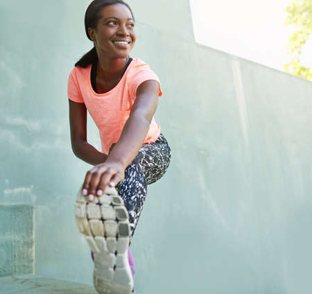 Looking forward to her workout. Full length shot of an attractive young woman stretching outdoors.