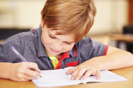 Happy to do his homework. A cute little boy doing his homework in class.の写真素材