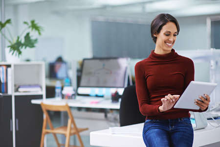 Technology that simplifies business. Shot of a happy young businesswoman using her tablet while...