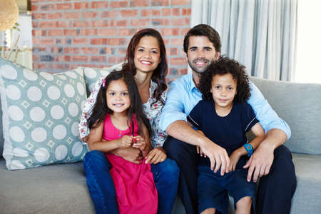 My happy family. A young family sitting on the couch together in their living room.の写真素材