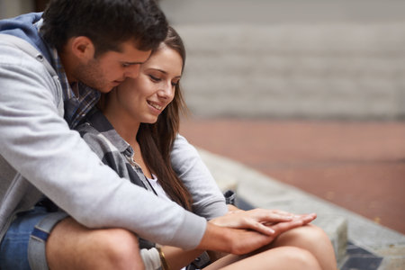 Sharing an intimate moment. A happy young couple sitting outside having an intimate moment.