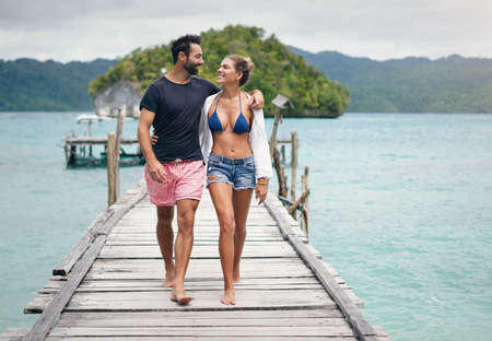 I love the way he looks at me. Full length shot of a happy young couple walking arm in arm down a...