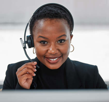Put yourself in their shoes. Shot of a young woman using a headset and computer.at work in a modern...