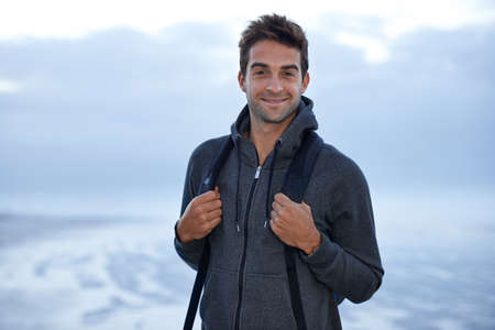 Here for inspiration. A handsome young man standing on the beach at evening time.の写真素材
