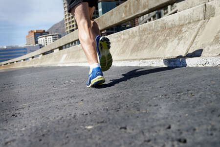 Taming the road. Cropped image of a runners legs as he runs onwards.