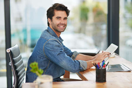 Working to turn his vision into profit. Cropped shot of a creative businessman working on his tablet...