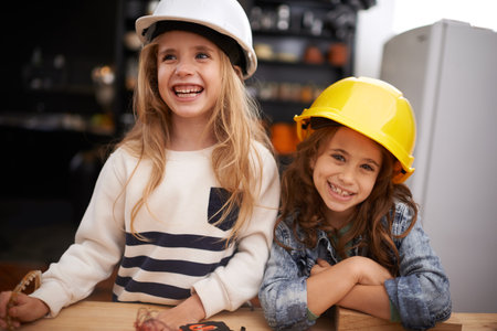 Creating things is so much fun. Shot of two little girls playing around with tools in hard hats.