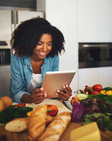Looks like Im doing everything right. Shot of a cheerful young woman browsing on a digital tablet...
