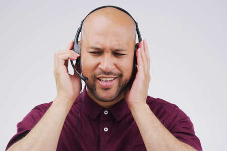 Efficient response is what great customer relationships are built on. Studio shot of a handsome young male customer service representative wearing a headset against a grey background.の写真素材