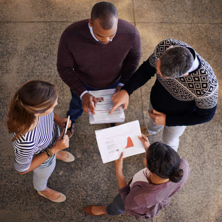 Making strategic decisions as a team. High angle shot of a group of colleagues discussing paperwork...