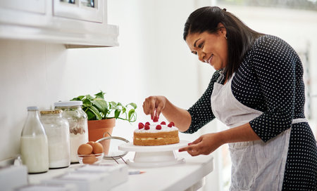 Theres nothing I love more than baking. Cropped shot of a woman decorating a cake in her kitchen.の写真素材
