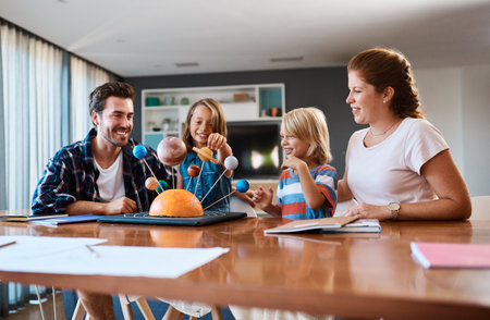 Shes taking us on a journey through the galaxy. Shot of a beautiful young family working together on a science project at home.の写真素材