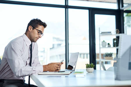 I know just who to call. Shot of a businessman using his cellphone while sitting at his desk.