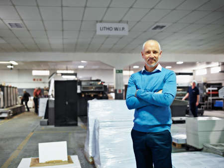 This is my factory and Im proud of it. Portrait of a man standing proudly in a printing factory.の写真素材