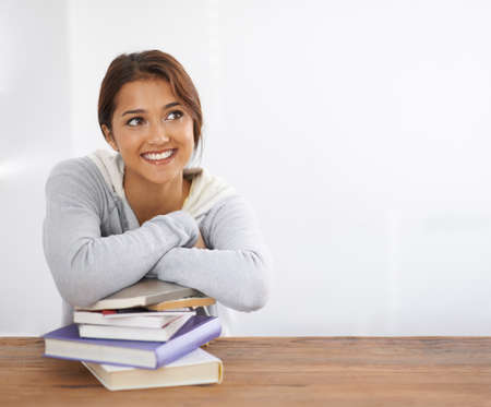 Finding the solution to a problem. Shot of a beautiful college student leaning on her books at her...