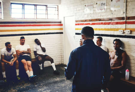 So heres what were going to do.... Cropped shot of a rugby coach addressing his team players in a locker room during the day.の写真素材