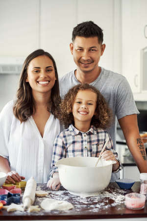 A bond everyone strives for. Portrait of an adorable little girl baking with her parents at home.の写真素材