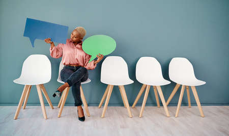 What are you saying dear. Studio shot of an attractive young businesswoman holding up speech bubbles...