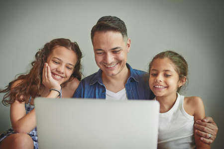 Shot of a man and his two daughters looking at something on a laptop.の写真素材