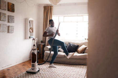 Shot of a young man dancing while busy vacuuming the living room.の写真素材