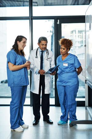Diagnosis done with teamwork. Shot of a team of doctors discussing the results of an X-ray in a hospital.の写真素材
