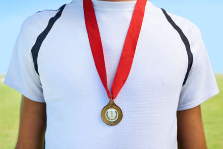 Wearing the gold proudly. Cropped shot of a gold medal around an athletes neck.の写真素材