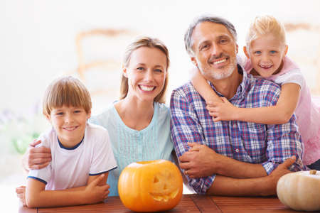 The family carving. Portrait of a family of four sitting with their jack-o-lantern at home.の写真素材