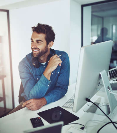 Hes on top of his work. High angle shot of a handsome young businessman looking thoughtful while...