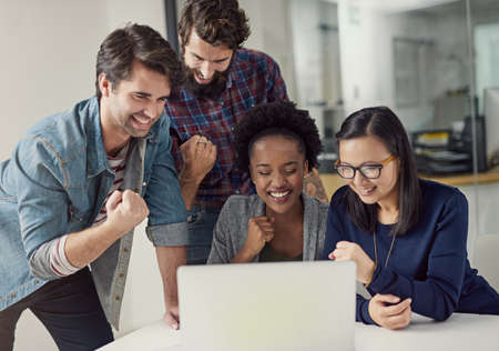 Feeling the benefits of being team players. Shot of a group of designer gathering to look at...