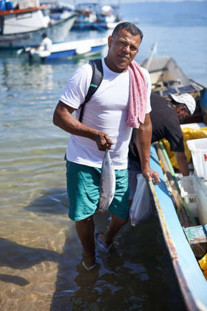 Fishing is my life. Portrait of a fisherman standing in the water next to his boat.の写真素材