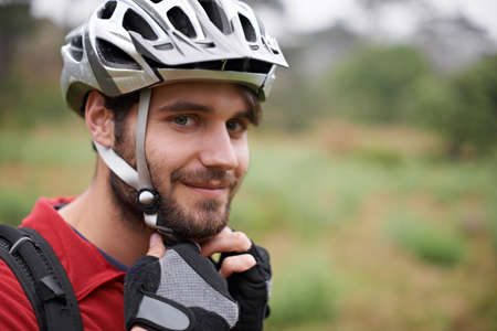 Its on tight. A young cyclist fastening his helmet.の写真素材