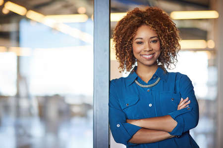 Entrepreneurs doing what they do best. Portrait of a smiling young professional standing in a modern office.の写真素材