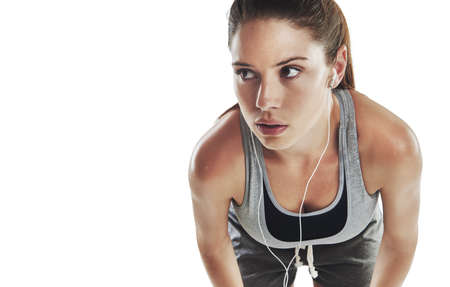 Motivated by music. Cropped shot of a young female athlete listening to music against white...