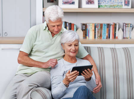 What a nifty little device. A senior couple relaxing in their home with a digital tablet.