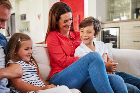 Family bonds. Shot of smiling parents sitting with their young son and daughter on their living room...