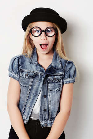 Pulling a face. Portrait of a young girl wearing big round glasses posing in the studio.の写真素材