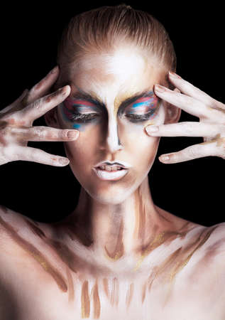 Channeling her colourful spirit. Studio shot of a young woman posing with paint on her face isolated...