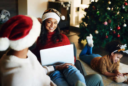 The best time to be ho-ho-home. Shot of a young man and woman using a laptop with their daughter playing in the background during Christmas at home.の写真素材