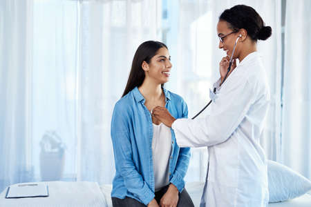 Strong set of lungs you have there. Shot of a young doctor examining her patient with a stethoscope.の写真素材