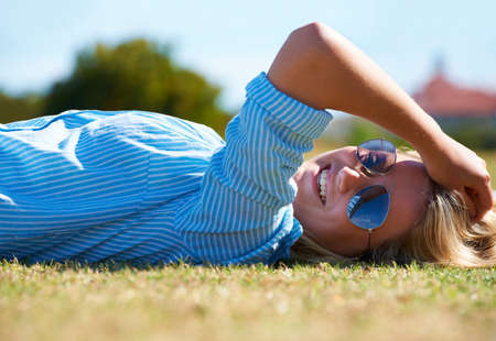 Summers finally here. A happy woman lying on a patch of grass in the sunshine.