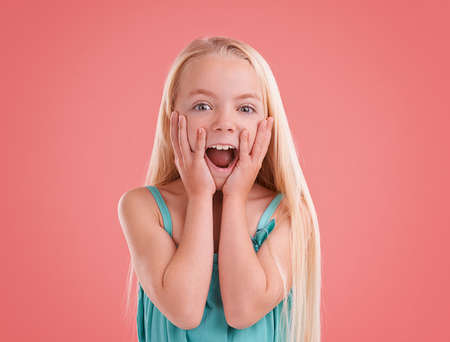 Look at that.... Studio shot of a young girl posing on an orange background.の写真素材