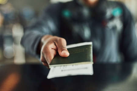 Have passport. Will travel. Shot of an unrecognizable person holding his passport indoors.の写真素材