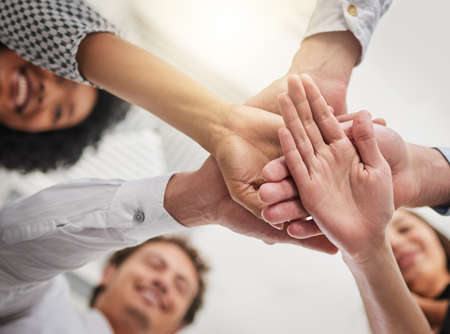 Together is the way forward. Low angle shot of a group of colleagues joining hands in solidarity in...