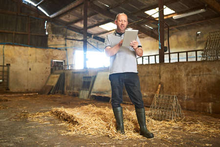 Keeping track of everything on the farm with technology. Full length shot of a male farmer using a...