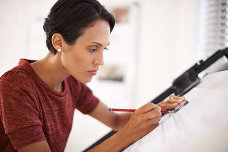 These plans are coming along nicely. Shot of an attractive young architect working in her office.