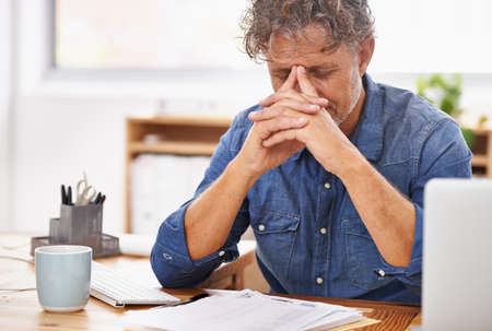 Im getting too old for this.... Shot of a mature businessman looking tired while working at his...