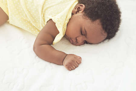 Sleeping peacefully. Cropped shot of a baby girl asleep on a bed at home.の写真素材