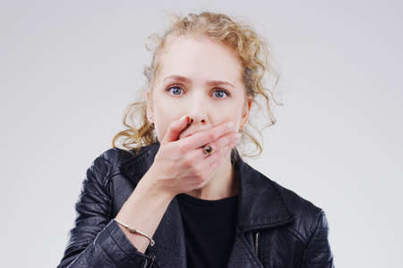 No way Tell me more. Studio shot of a young woman looking shocked against a grey background.の写真素材